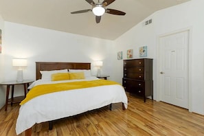 A bedroom with a bed, a dresser, a ceiling fan, and a door. - La Quinta Cove Oasis | Private Pool & Mountain Views (La Quinta)