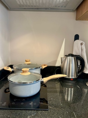 A kitchen with a stove, pots, and a kettle. - Level Brooklin 1217 (São Paulo)