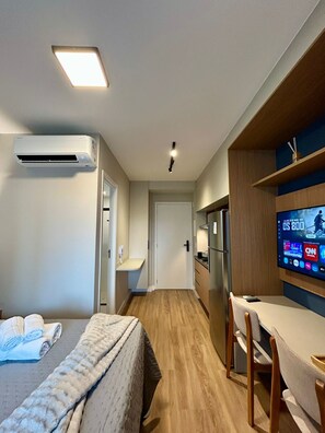 Une chambre d’hôtel équipée d’un lit, d’un bureau, d’une télévision et d’un climatiseur.
