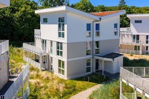 A multi-story residential building with a flat roof, large windows, and a balcony. - Dune Villa 02, Apartment 02 (Lübeck-Travemünde)