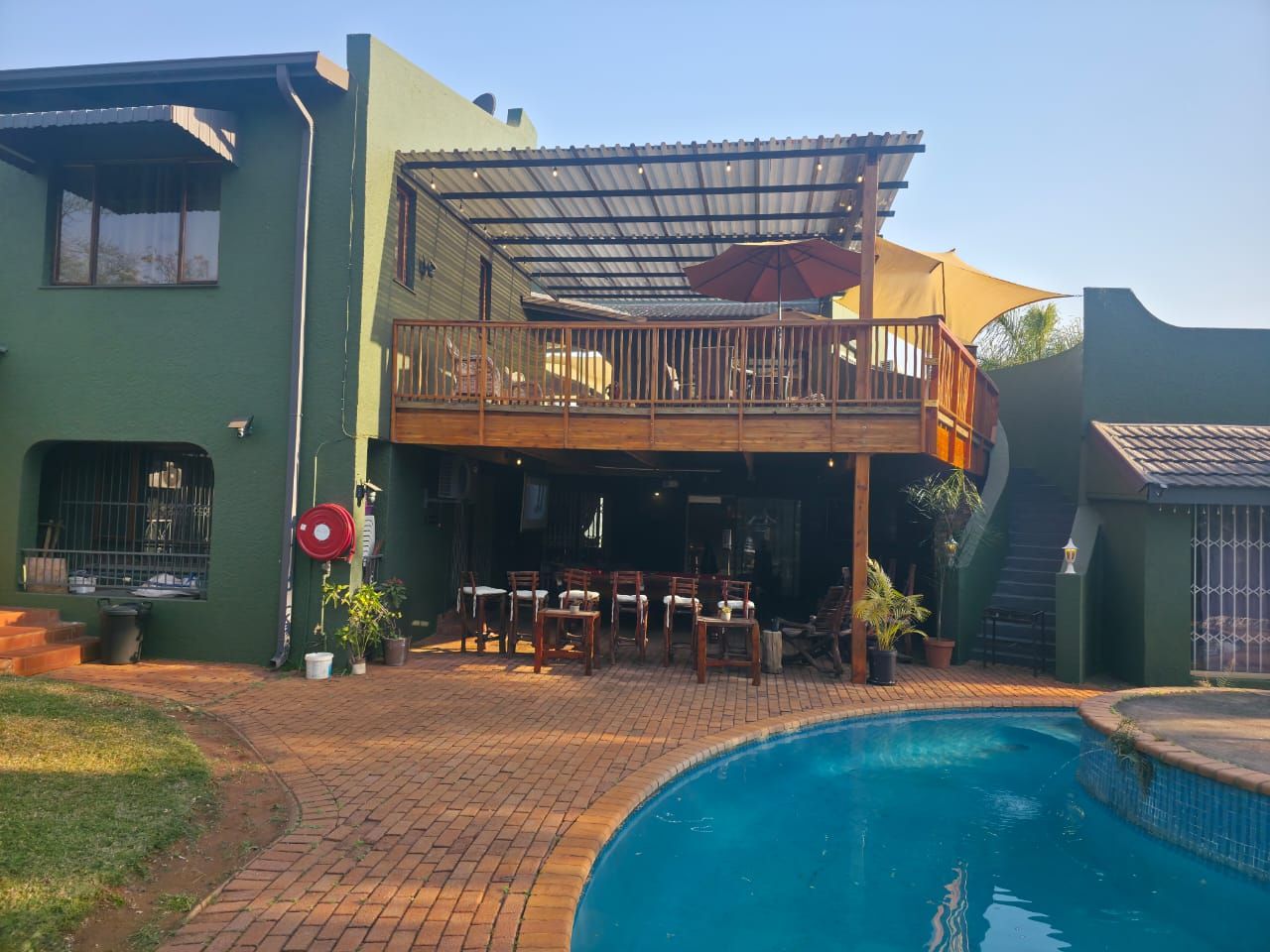 A two-story building with a pool, outdoor seating, and a covered patio area.