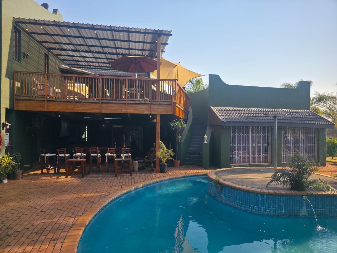 A poolside area with a covered seating area and a separate building with barred windows.