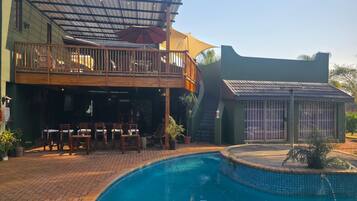 A poolside area with a covered seating area and a separate building with barred windows.