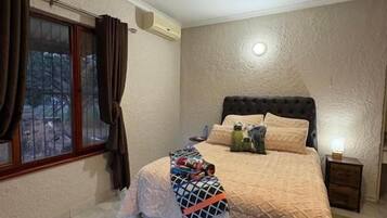 Un dormitorio con una cama, un ventilador de techo, una ventana con cortinas y un tapiz de cuero de vaca.