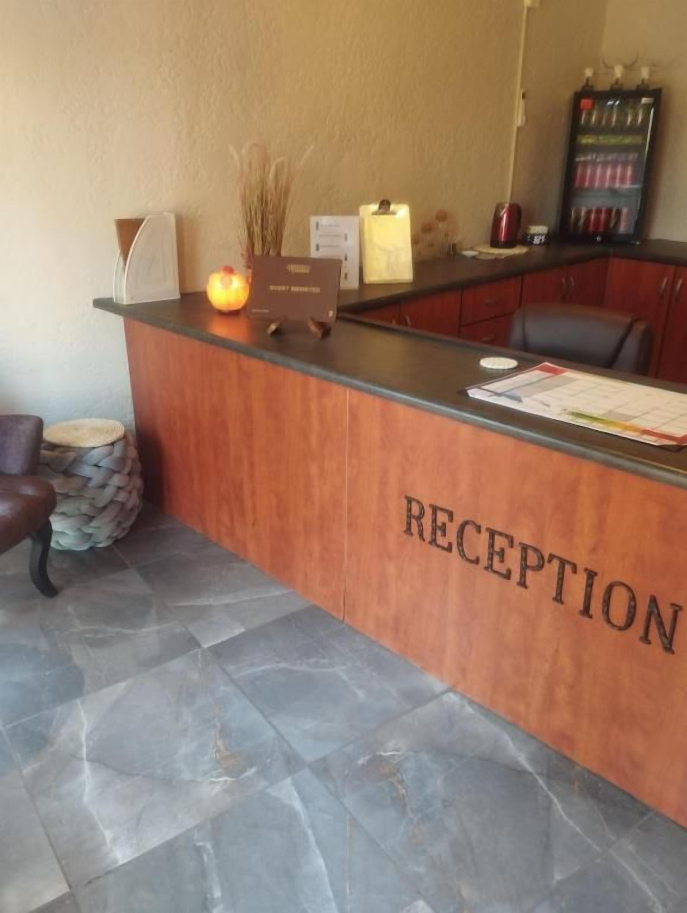 A reception desk with a sign that reads 'RECEPTION' and a counter with various items including a lamp, a vase with dried plants, and a menu.