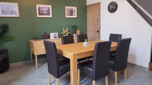 Ein Essbereich mit Holztisch, schwarzen Stühlen, gerahmten Bildern an der Wand und einer Uhr.
