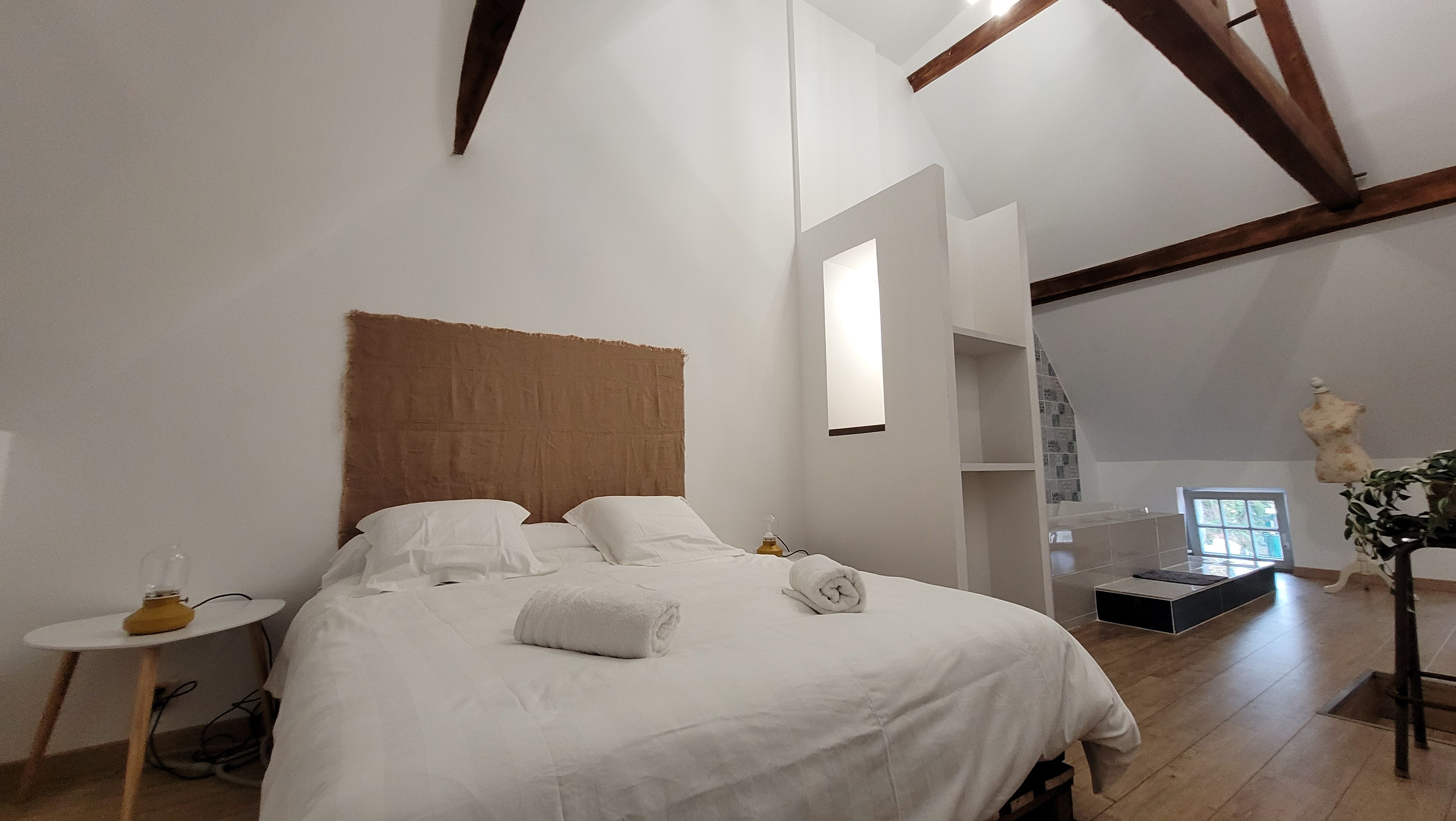 Une chambre à coucher avec un lit, une table de chevet et une petite fenêtre.