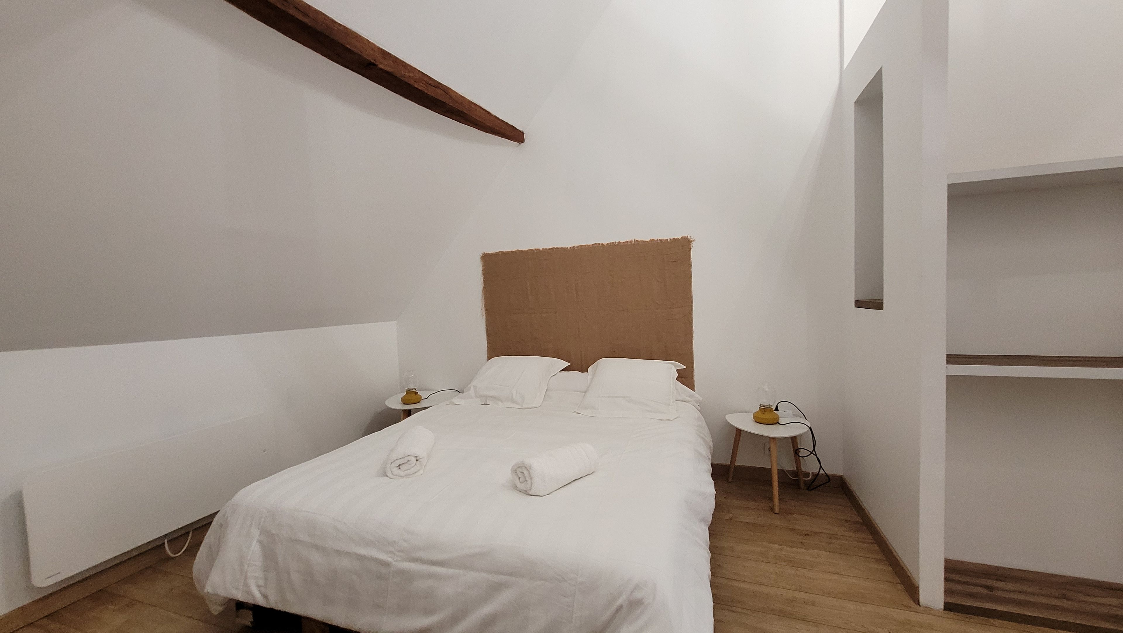 A minimalist bedroom with a bed, bedside tables, and a built-in shelf.