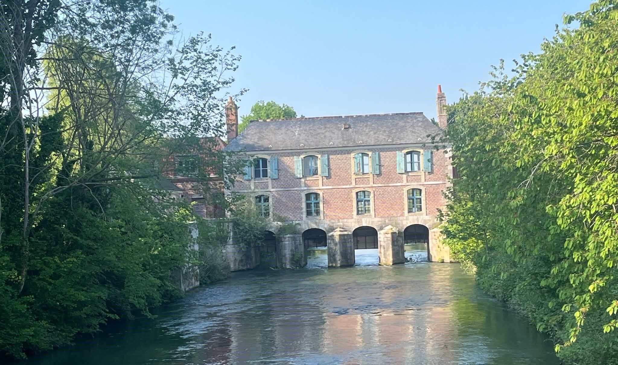 Ein historisches Gebäude mit mehreren Bögen und einem Fluss davor.