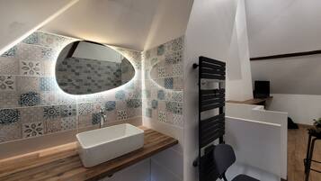 A modern bathroom with a freestanding sink, a mirror, and a shower area.