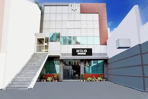 A modern hotel with a prominent 'HOTEL' sign, a staircase leading to the entrance, and potted plants at the base. - Hotel O Rohini Sector 20 Formerly (Delhi)