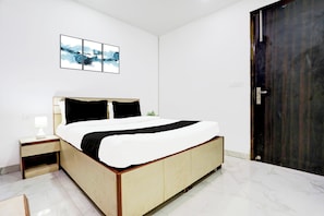 Une chambre à coucher avec un lit, une table de chevet, une lampe et une porte.