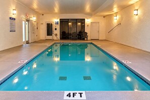 En swimmingpool med en markering som visar ett djup på 4 fot, omgiven av väggar med belysning och en dörr med skylten ”UTGÅNG”.