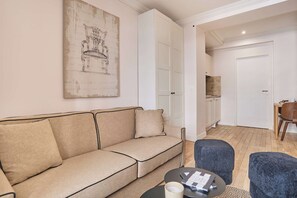 Ein Wohnzimmer mit einem beigefarbenen Sofa, einem Couchtisch und einem blauen Hocker.