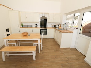 Eine kompakte Küche mit weißen Schränken, einem Holztisch und einem eingebauten Backofen.