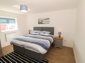 Ein modernes Schlafzimmer mit einem Bett, Nachttischen, einem Fenster und einem Bild an der Wand.