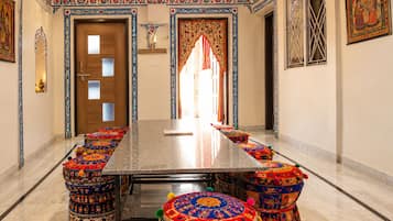 A long, rectangular table with a marble top, surrounded by colorful, patterned ottomans.
