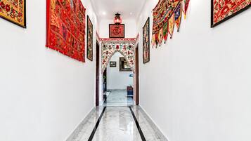 A hallway with a marble floor, framed artwork on the walls, and a decorative archway.