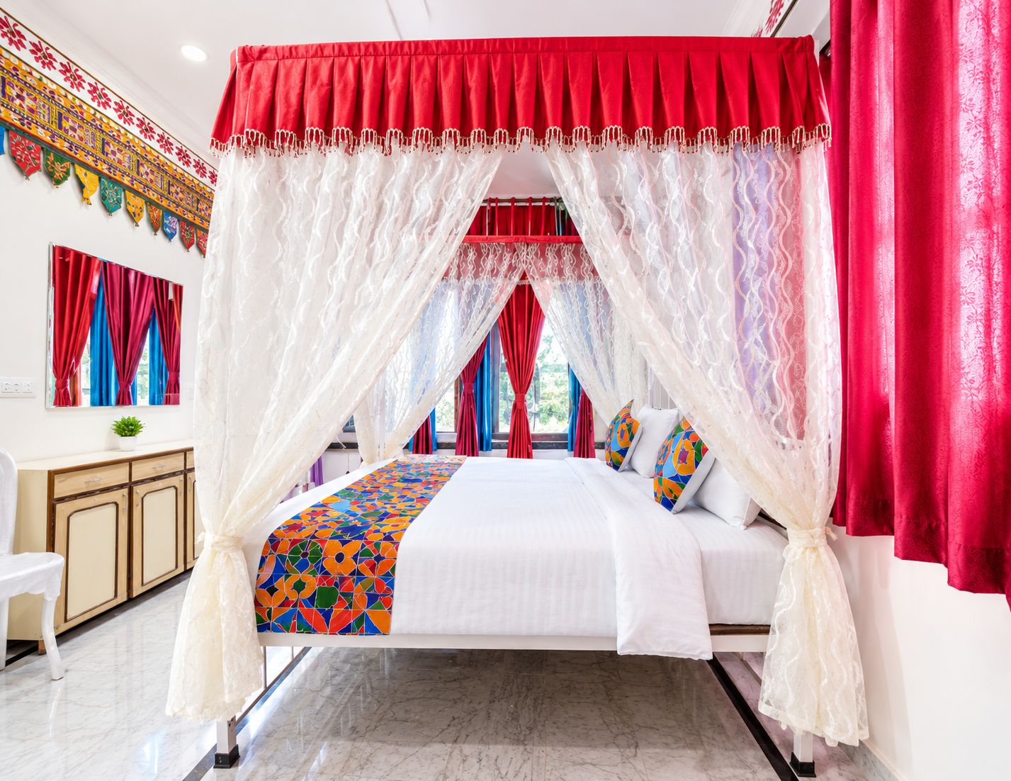 A bed with a canopy, a desk, and a chair in a room with a patterned wall.