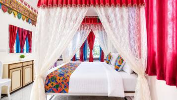 A bed with a canopy, a desk, and a chair in a room with a patterned wall.