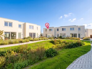 Un immeuble résidentiel moderne doté d’un chemin pavé et d’un espace vert bien entretenu.