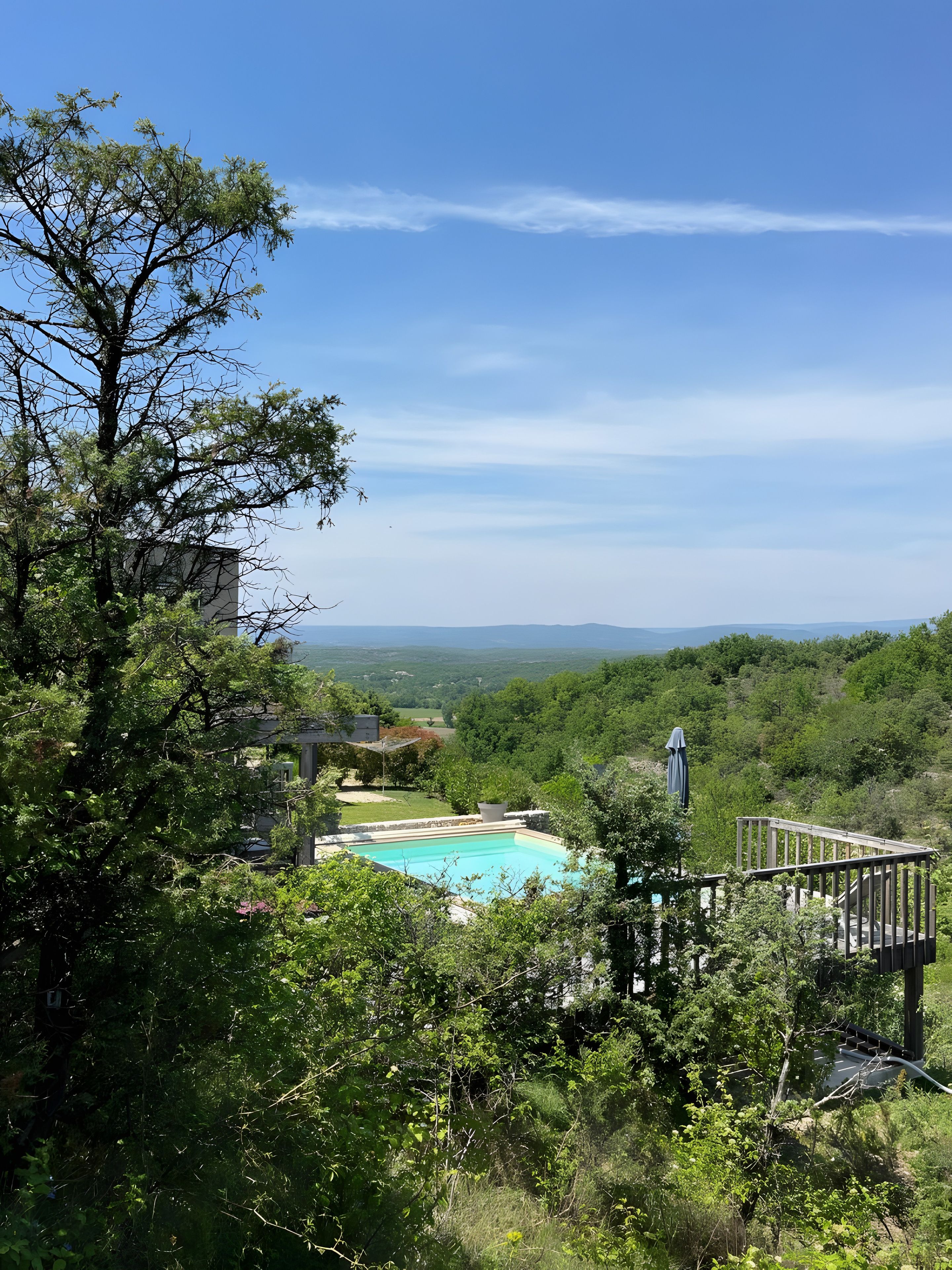 Piscina rodeada de exuberante vegetación, con vistas despejadas a colinas distantes.