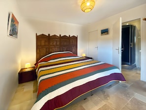 Ein Schlafzimmer mit einem großen Bett, einem Holzkopfstück, einem Nachttisch mit Lampe und einer Tür zu einem Badezimmer.