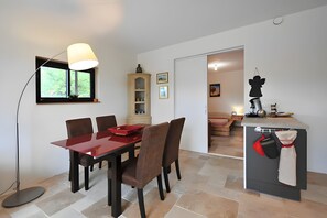 Ein Essbereich mit Tisch und Stühlen, eine Vitrine und eine Küchenzeile mit Spüle und Arbeitsplatte.