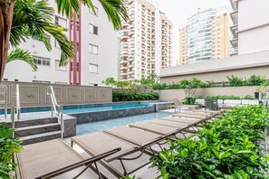 A rooftop pool area with lounge chairs, a swimming pool, and surrounding greenery. - Maison Perdizes 605 (São Paulo)