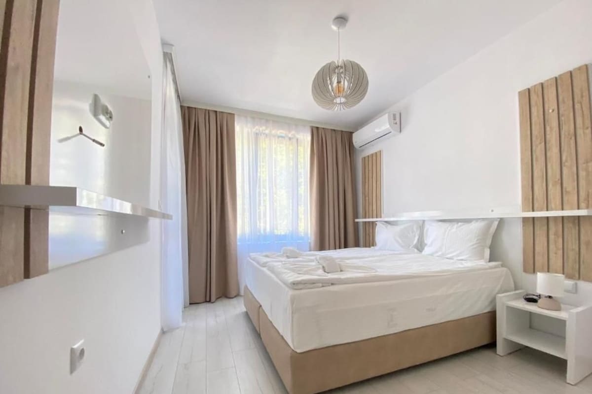 A modern bedroom with a bed, bedside table, and a hanging light fixture.