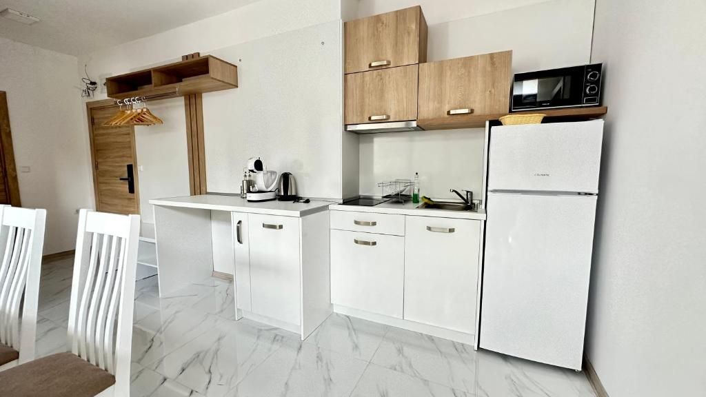 Una cocina moderna con armarios blancos, microondas y refrigerador.