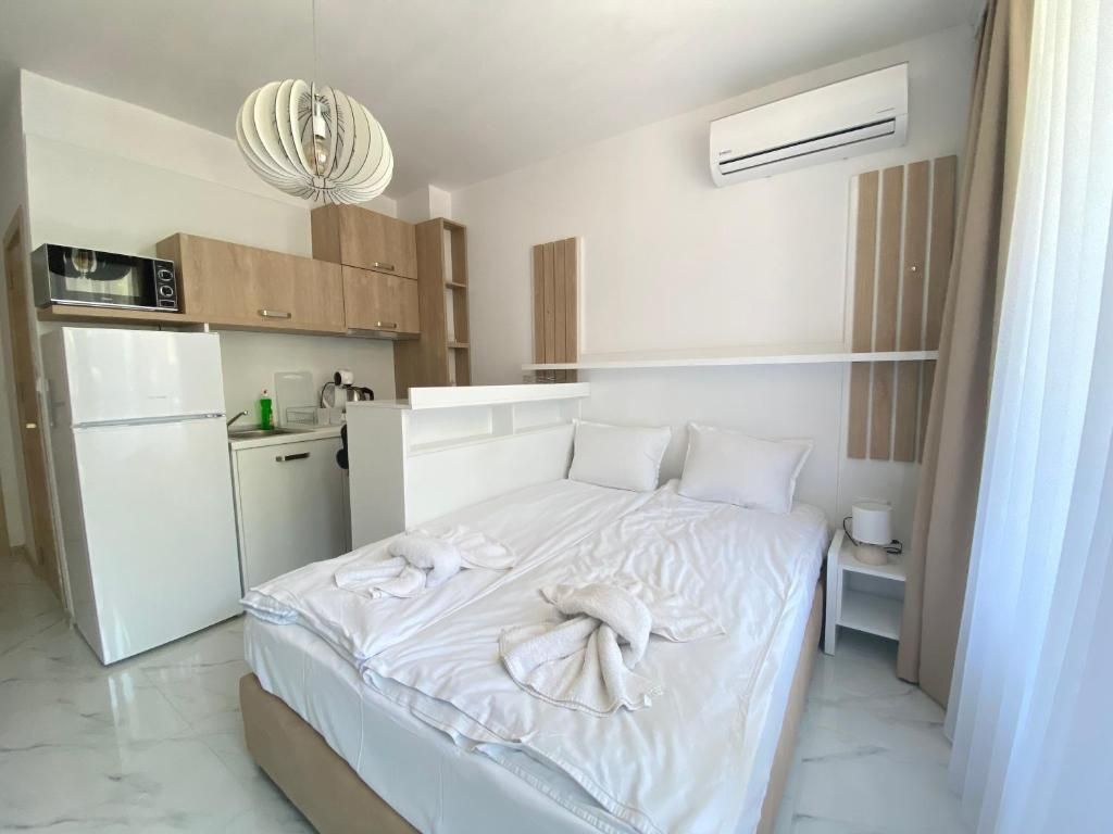 Habitación de hotel con cama, kitchenette pequeña y equipo de aire acondicionado.