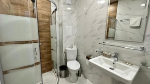 A modern bathroom with a glass shower enclosure, a toilet, a sink with soap dispensers, and a mirror. - The Green Paradise Apartments (Primorsko)