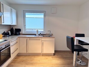Eine kleine Küche mit Fenster, Spüle und Herd.