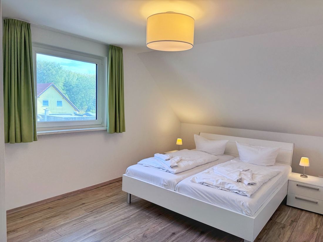 Ein Schlafzimmer mit einem Bett, Nachttischlampen und einem Fenster mit Vorhängen.