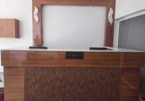 Uma mesa de recepção com uma placa indicando 'RECEPTION', acompanhada por duas peças decorativas na parede.