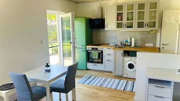 Una cocina compacta con zona de comedor, lavadora y refrigerador verde.