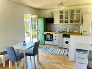 Eine kompakte Küche mit Essbereich, einer Waschmaschine und einem grünen Kühlschrank.