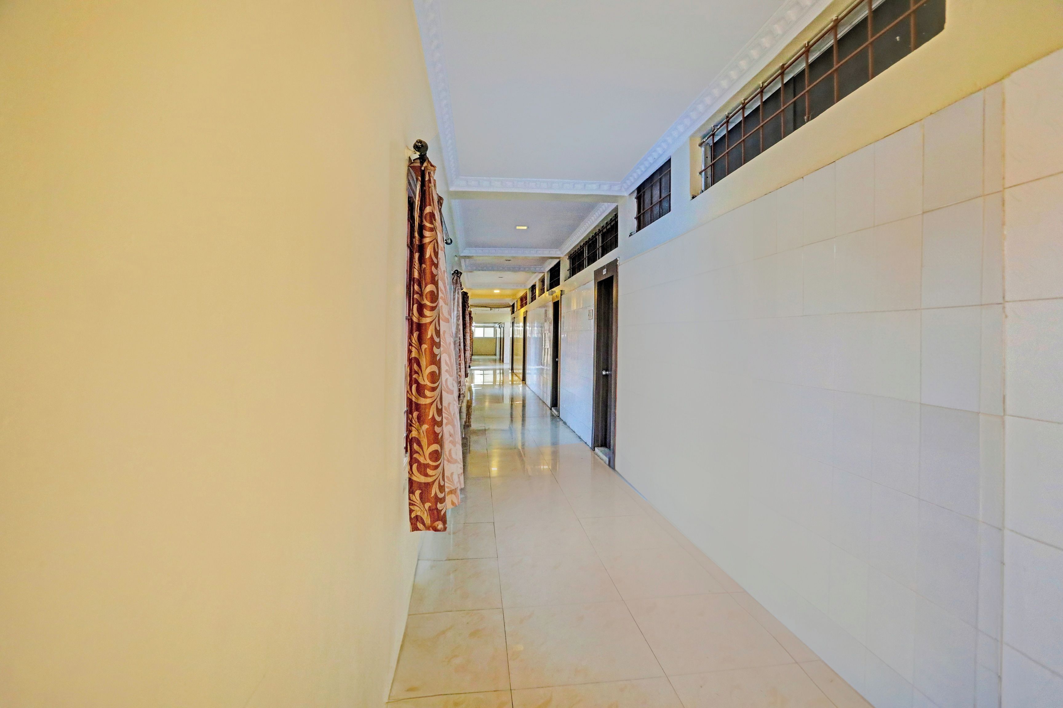 A corridor with a patterned curtain, tiled walls, and a ceiling with recessed lighting.