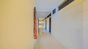 A corridor with a patterned curtain, tiled walls, and a ceiling with recessed lighting.
