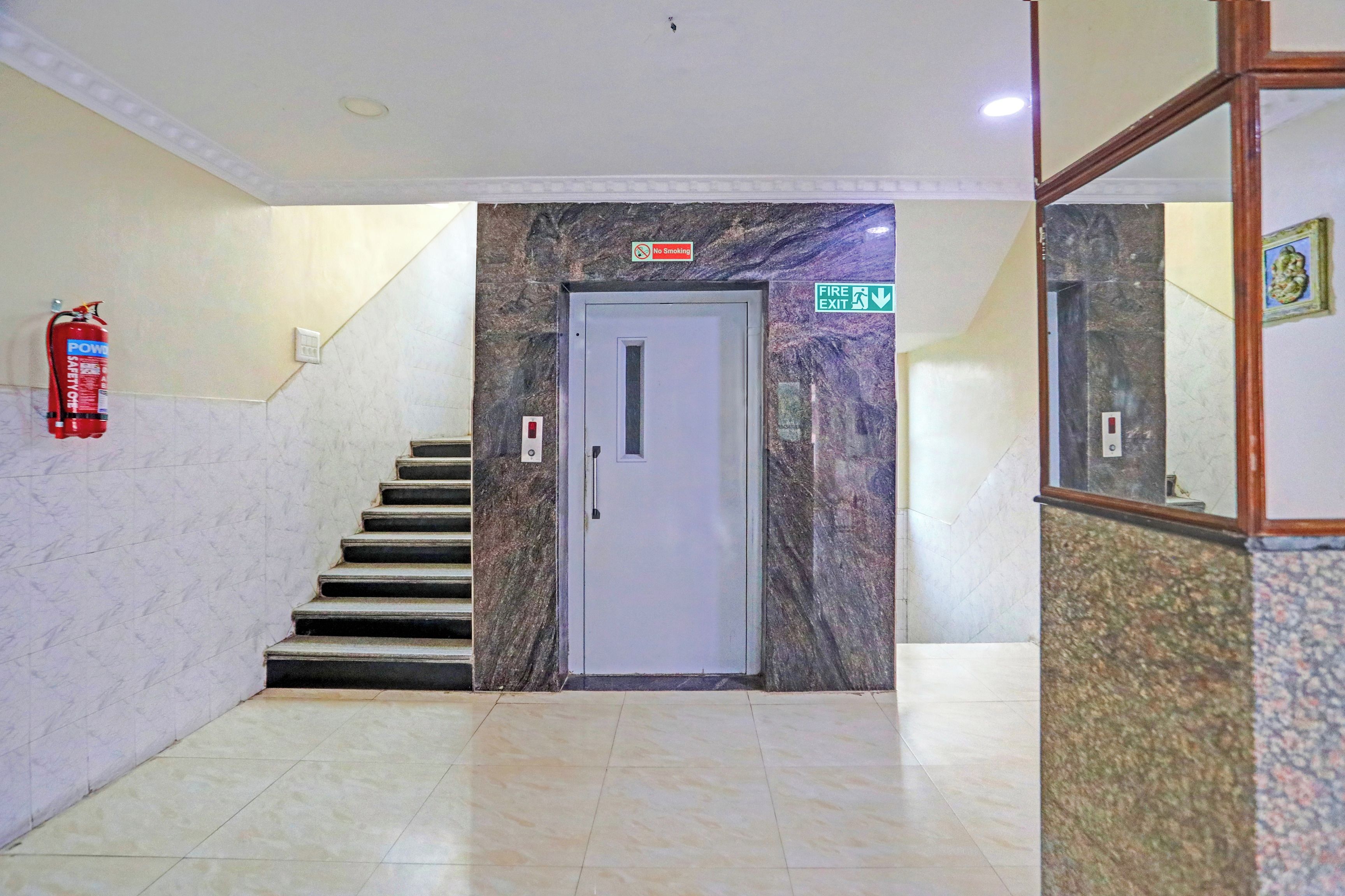 A stairway leading to a door with a 'No Smoking' sign above it, a fire exit sign, and a fire extinguisher on the wall.