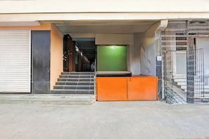 A building entrance with a closed shutter door, a set of stairs leading to a green door, and a metal gate. - Collection O Machilipatnam Bus Terminal (Machilipatnam)