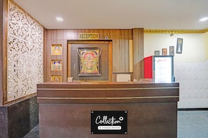 Ein Empfangsschalter mit einem 'RECEPTION'-Schild, gerahmte religiöse Kunstwerke und ein Coca-Cola-Kühlschrank.