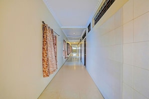 A long, narrow hallway with patterned curtains on the left and a tiled wall on the right.