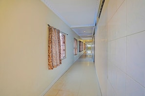 A long, narrow hallway with patterned curtains on the windows, tiled walls, and a tiled floor. - Collection O Machilipatnam Bus Terminal (Machilipatnam)