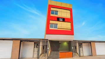 A multi-story building with a red and beige facade, a sign indicating 'Company Services,' and a set of stairs leading to a green-lit entrance.