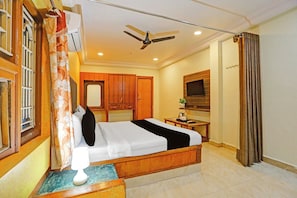 Una habitación de hotel con una cama, un escritorio, un televisor y un ventilador de techo.