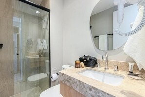 Ein modernes Badezimmer mit Duschkabine aus Glas, einem Waschbecken mit Marmorplatte und einem Spiegel mit aufgehängtem Handtuch an der Wand.