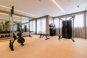 Ein Fitnessraum mit Trainingsgeräten, einer Bank und einem Spiegel.