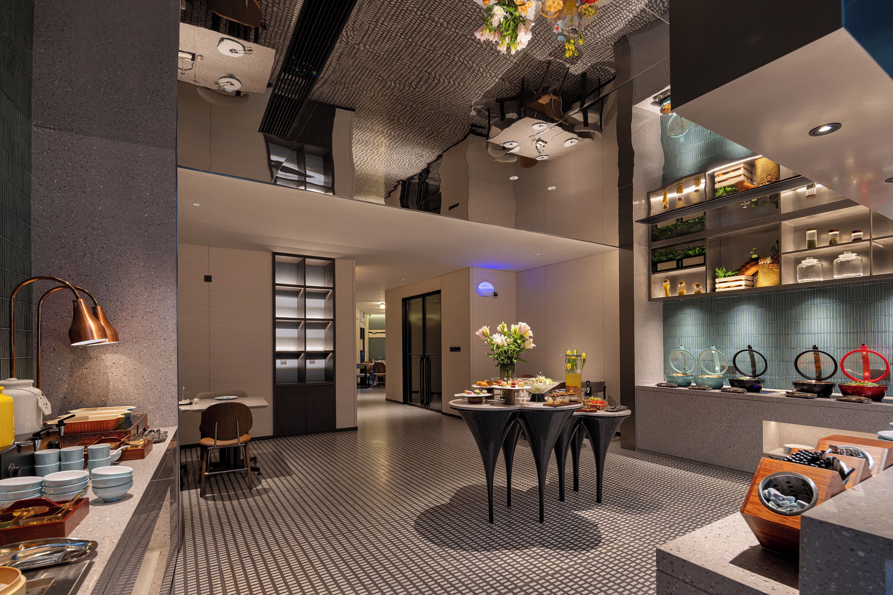 A modern hotel lobby with a central seating area, a reception desk, and a buffet setup.
